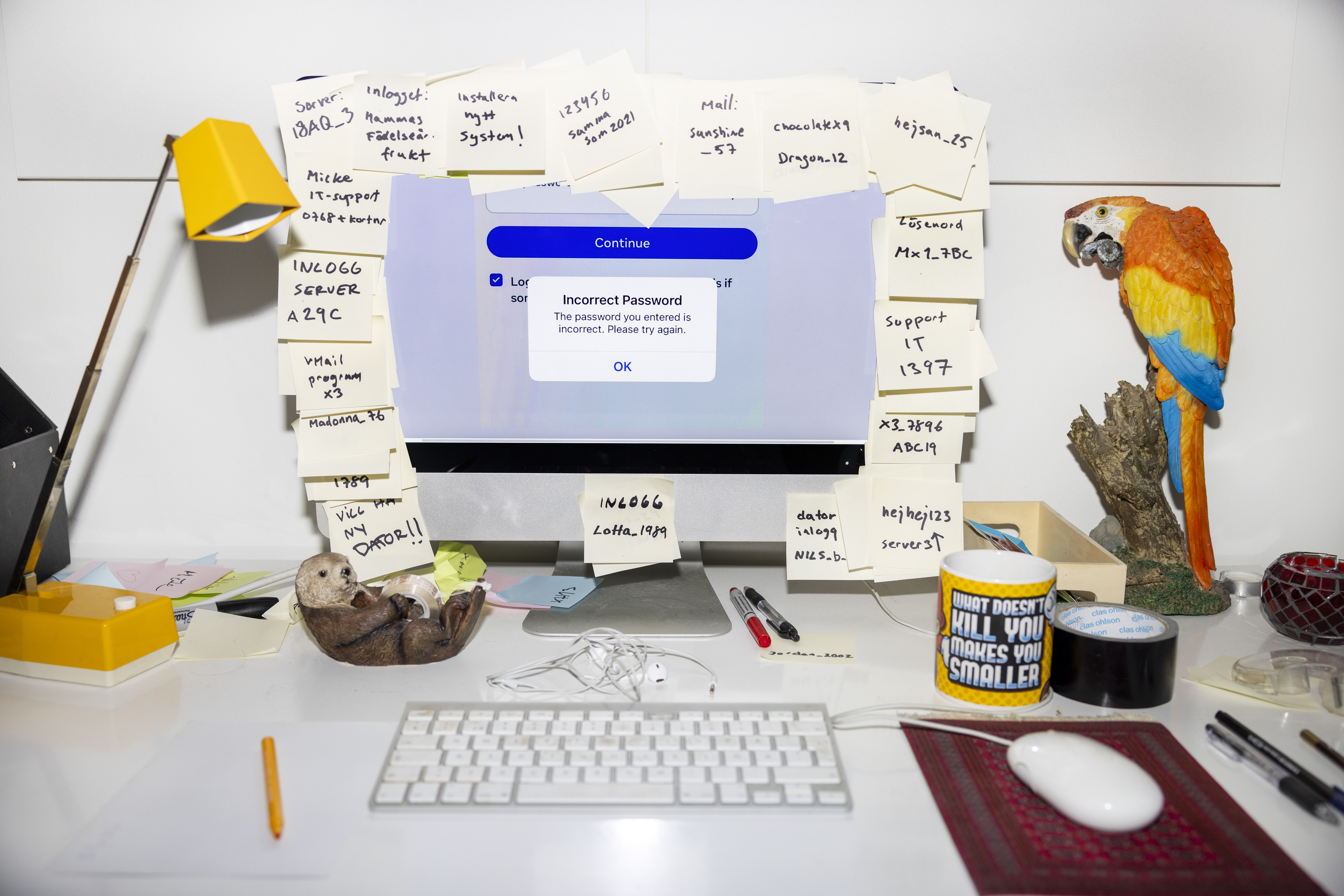 En datorskärm med postitlappar som en ram runt hela skärmen. På lapparna står olika inloggningsuppgifter och lösenord skrivna. Framför skärmen finns ett tangentbord och en datormus, bland annat. Foto: Daniel Nilsson